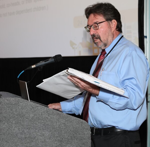 The Presenter standing at a podium speaking.