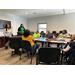 Men and women listening to a presenter while sitting around a table.