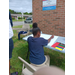 A little girl coloring her poster in with a red color pencil.