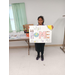 A girl posing with her poster where each letter for &quot;What Home Means to Me&quot; represents something different.