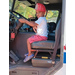 A child in a red firemans helmet sitting in a truck.