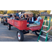 A group of people in a red wagon with the tailgate down by a ladder.