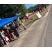 A group of people standing in a parking lot by a table.