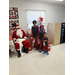 Santa sitting next to three children in front of a Christmas tree.