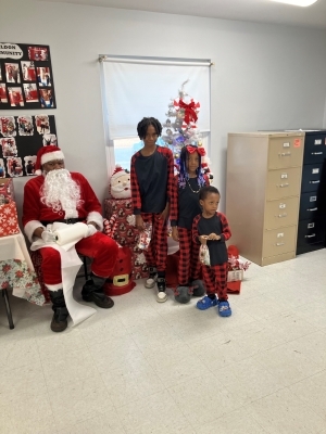 CookieswithSanta1.jpg Santa sitting next to three children in front of a Christmas tree.